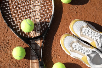 Tennis balls, racket and shoes on clay court, flat lay