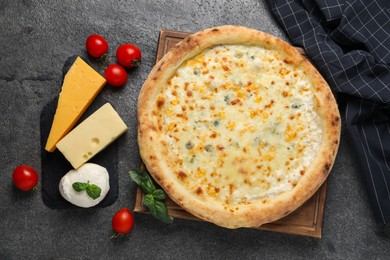 Photo of Delicious cheese pizza and ingredients on dark grey table, flat lay