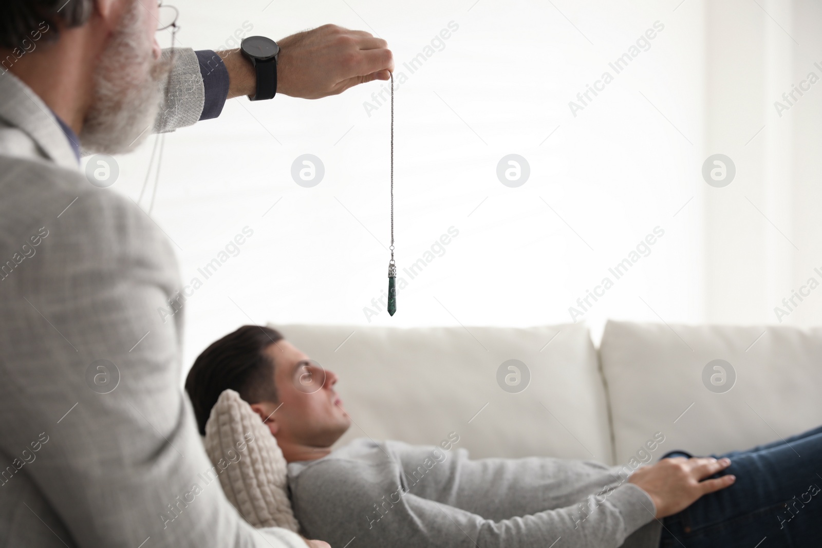 Photo of Psychotherapist using pendulum during hypnotherapy   session in office