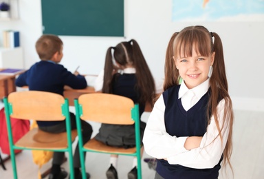 Little girl in classroom. Stylish school uniform