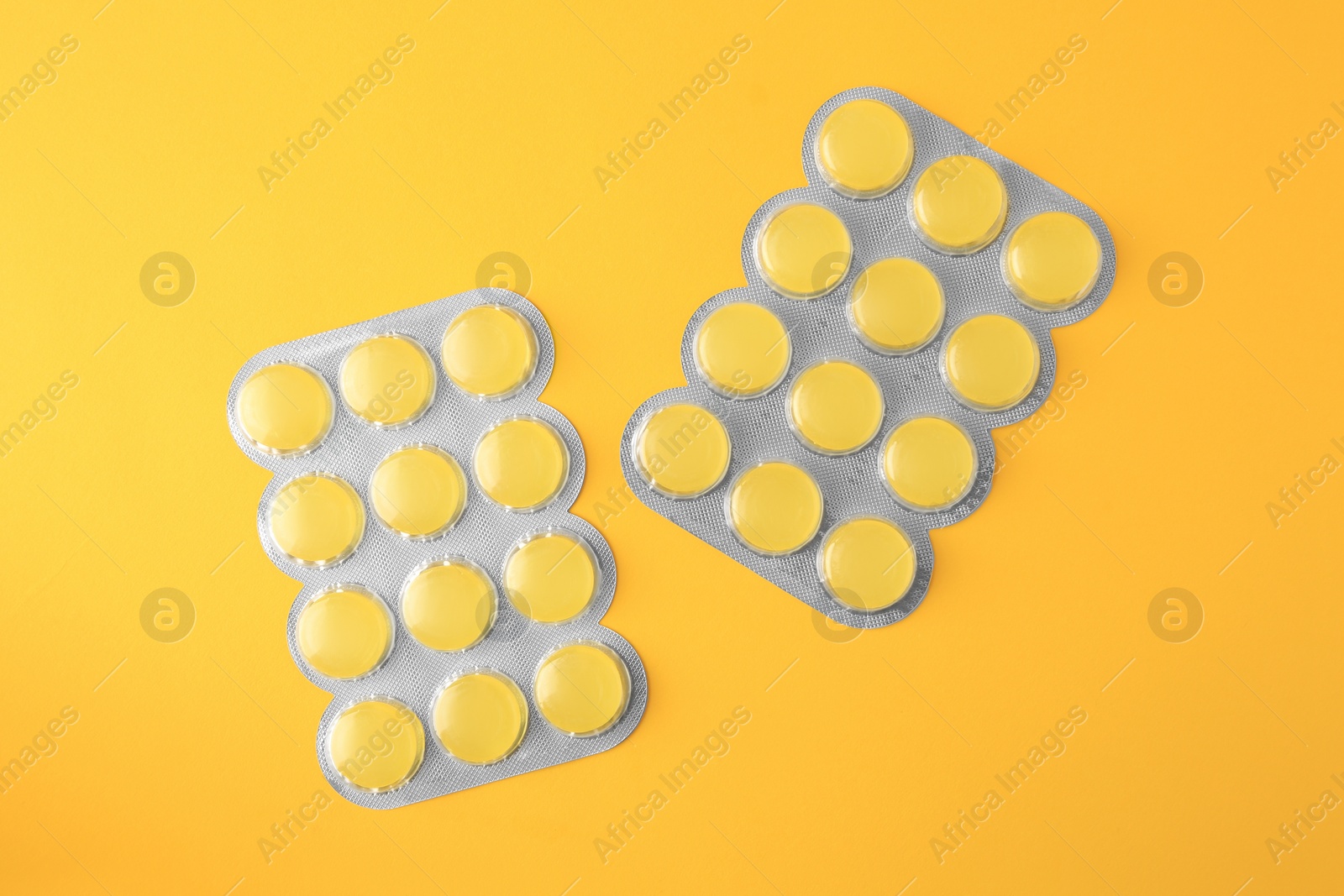 Photo of Blisters with cough drops on yellow background, flat lay