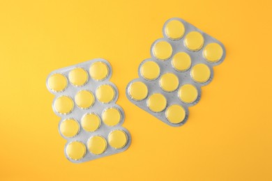 Photo of Blisters with cough drops on yellow background, flat lay