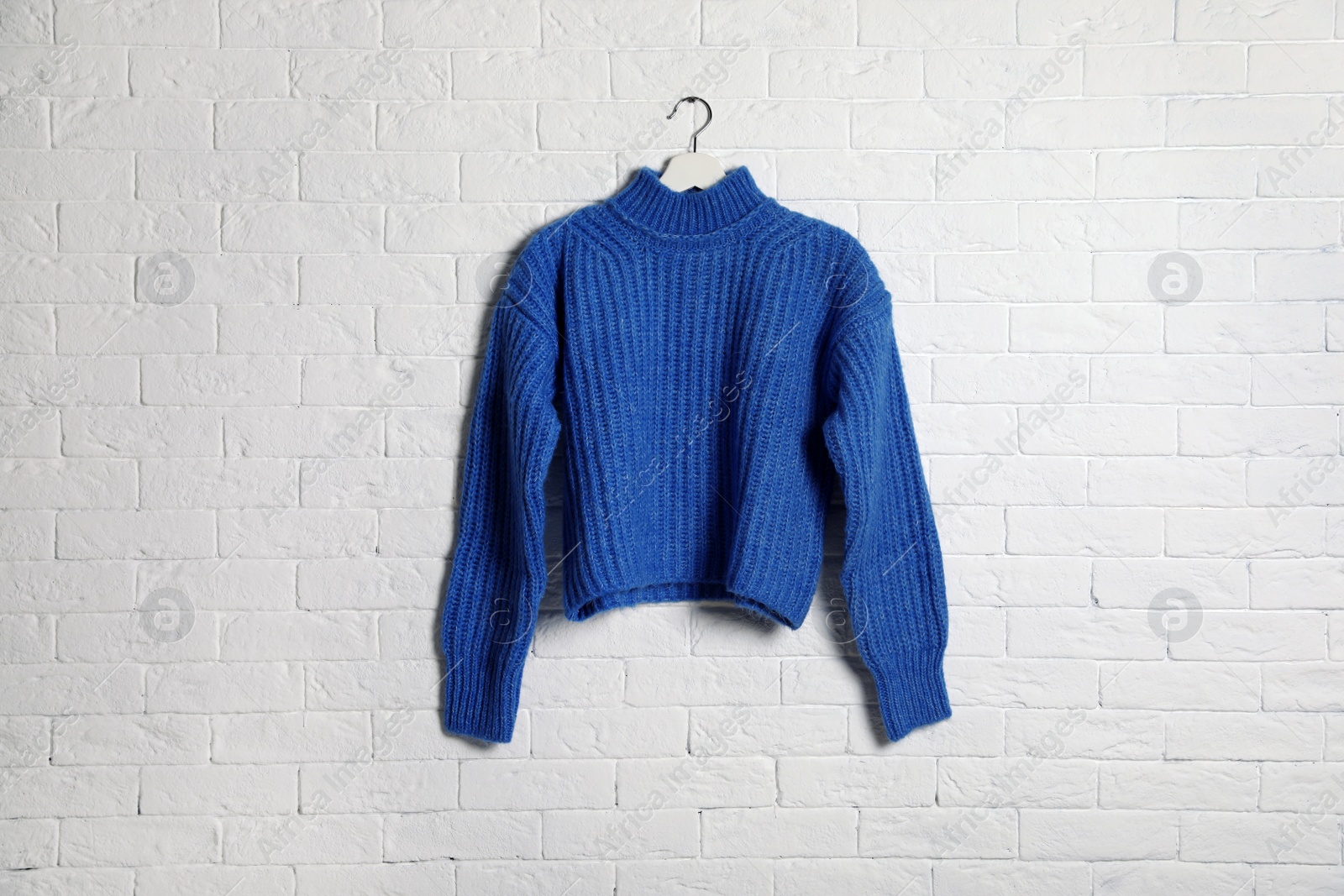 Photo of Hanger with stylish sweater on brick wall