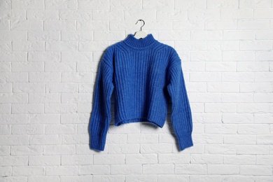 Photo of Hanger with stylish sweater on brick wall