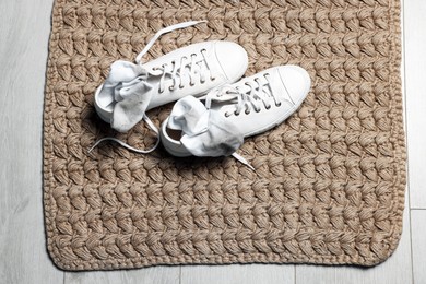 Sneakers with dirty socks on woven mat indoors, top view. Space for text