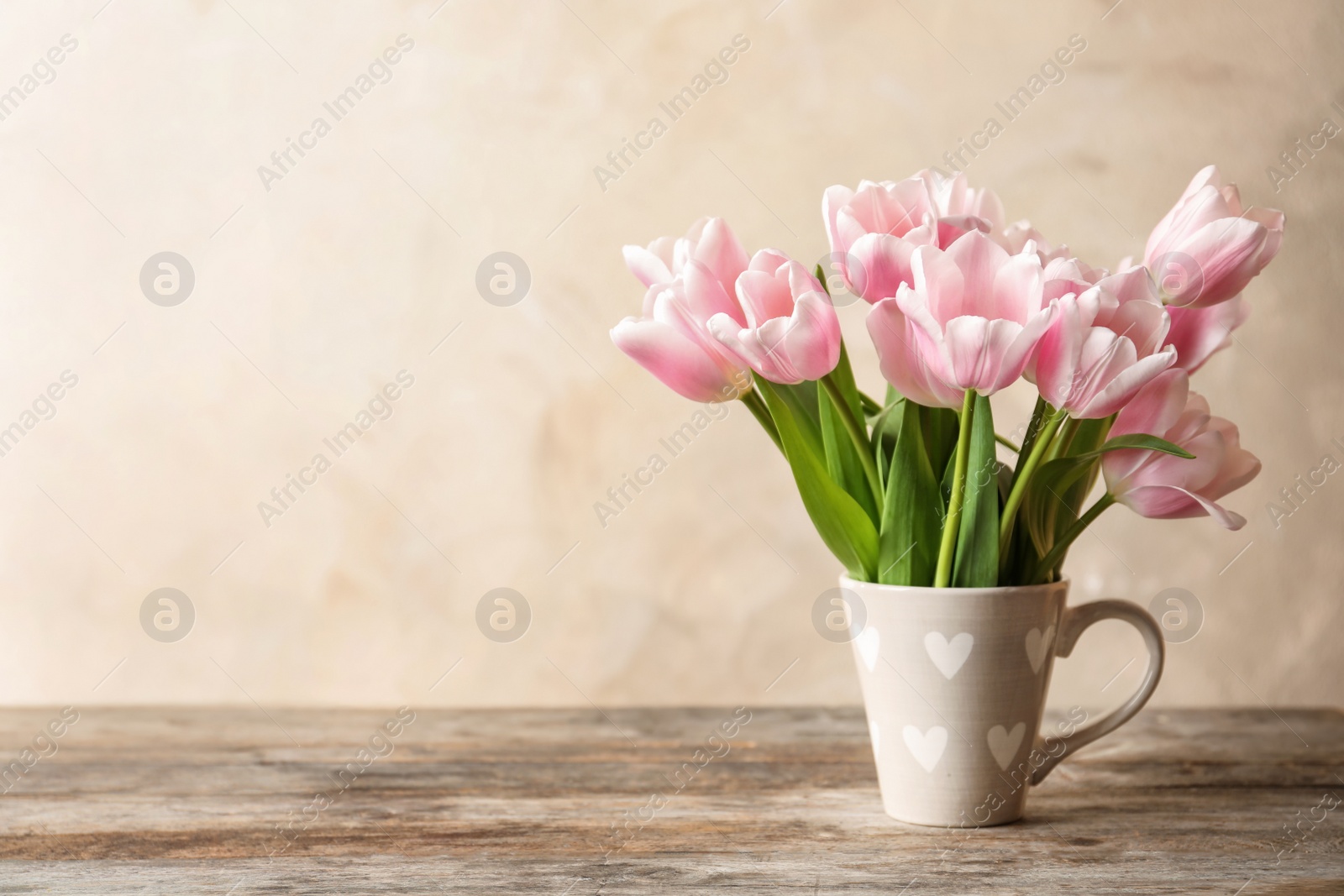 Photo of Cup with beautiful tulips for Mother's Day on table