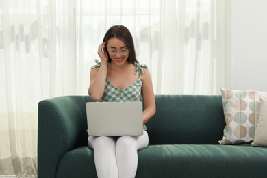 Young woman using laptop on sofa at home. Internet shopping