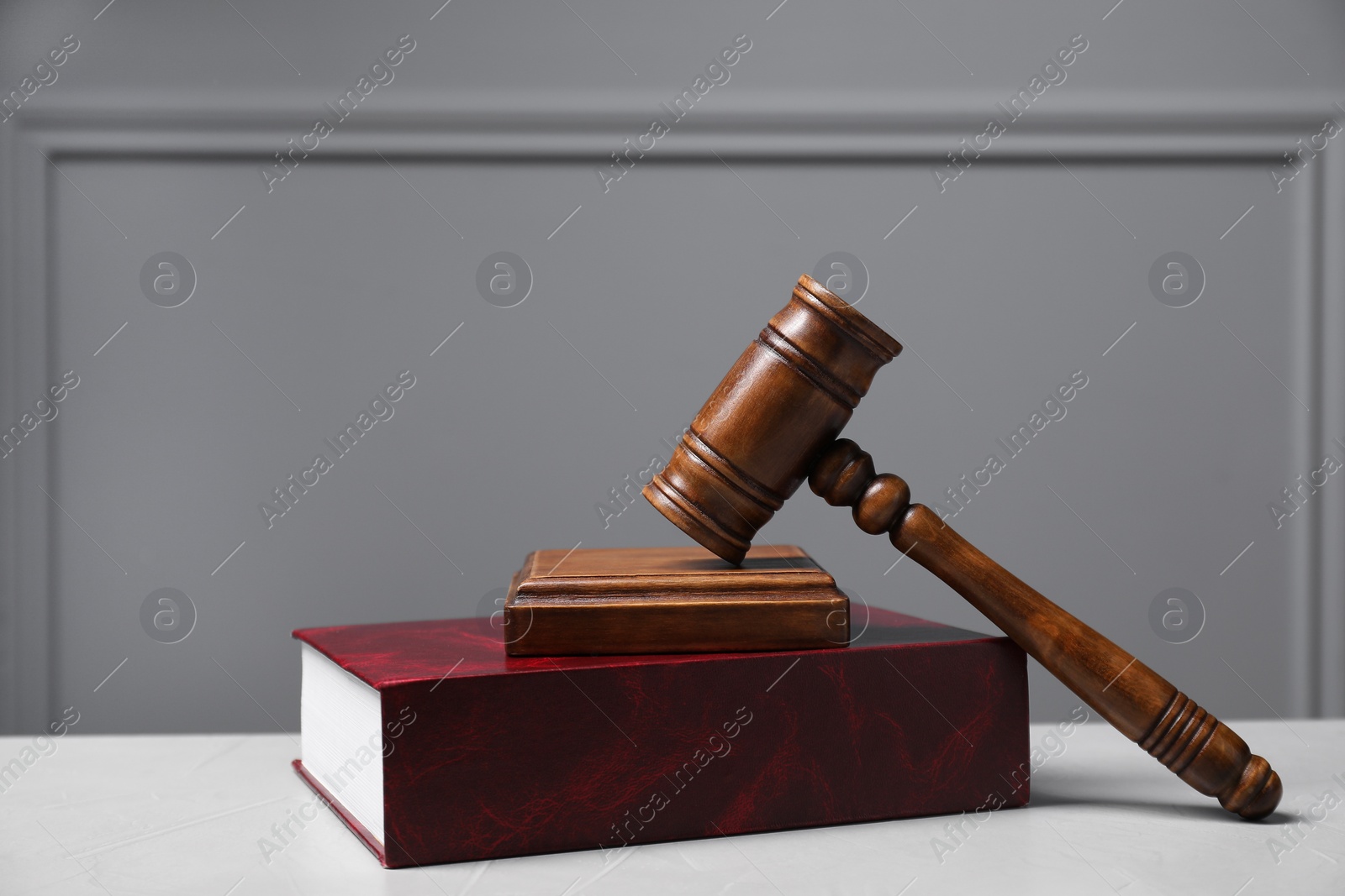 Photo of Law. Book, gavel and sound block on light table against gray background