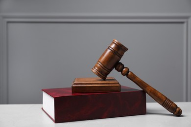 Law. Book, gavel and sound block on light table against gray background