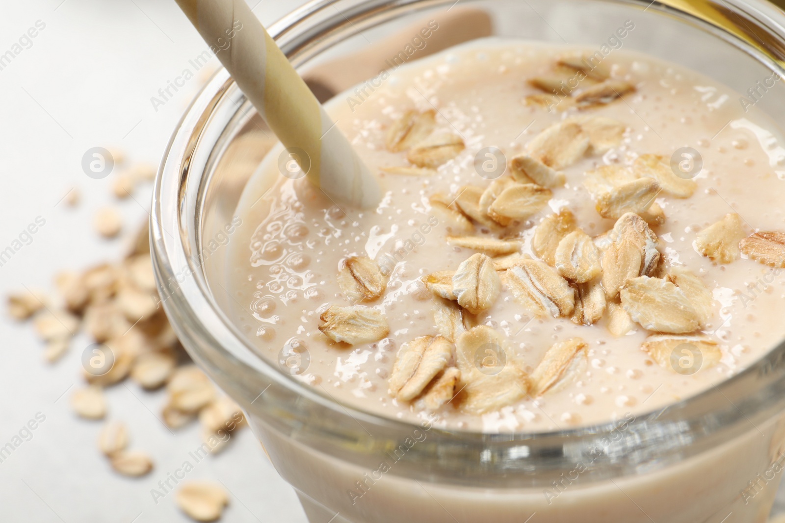 Photo of Glass of tasty smoothie with oatmeal on table, closeup