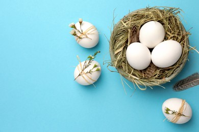 Nest, chicken eggs and natural decor on light blue background, flat lay with space for text. Happy Easter