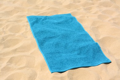 Photo of Beautiful soft blue towel on sandy beach