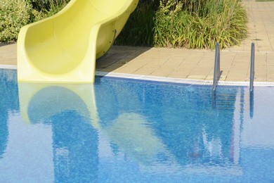 Photo of Outdoor swimming pool with handrails, ladder and waterslide on sunny day