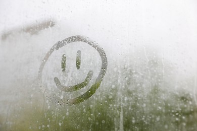 Photo of Funny face drawn on foggy window, space for text. Rainy weather