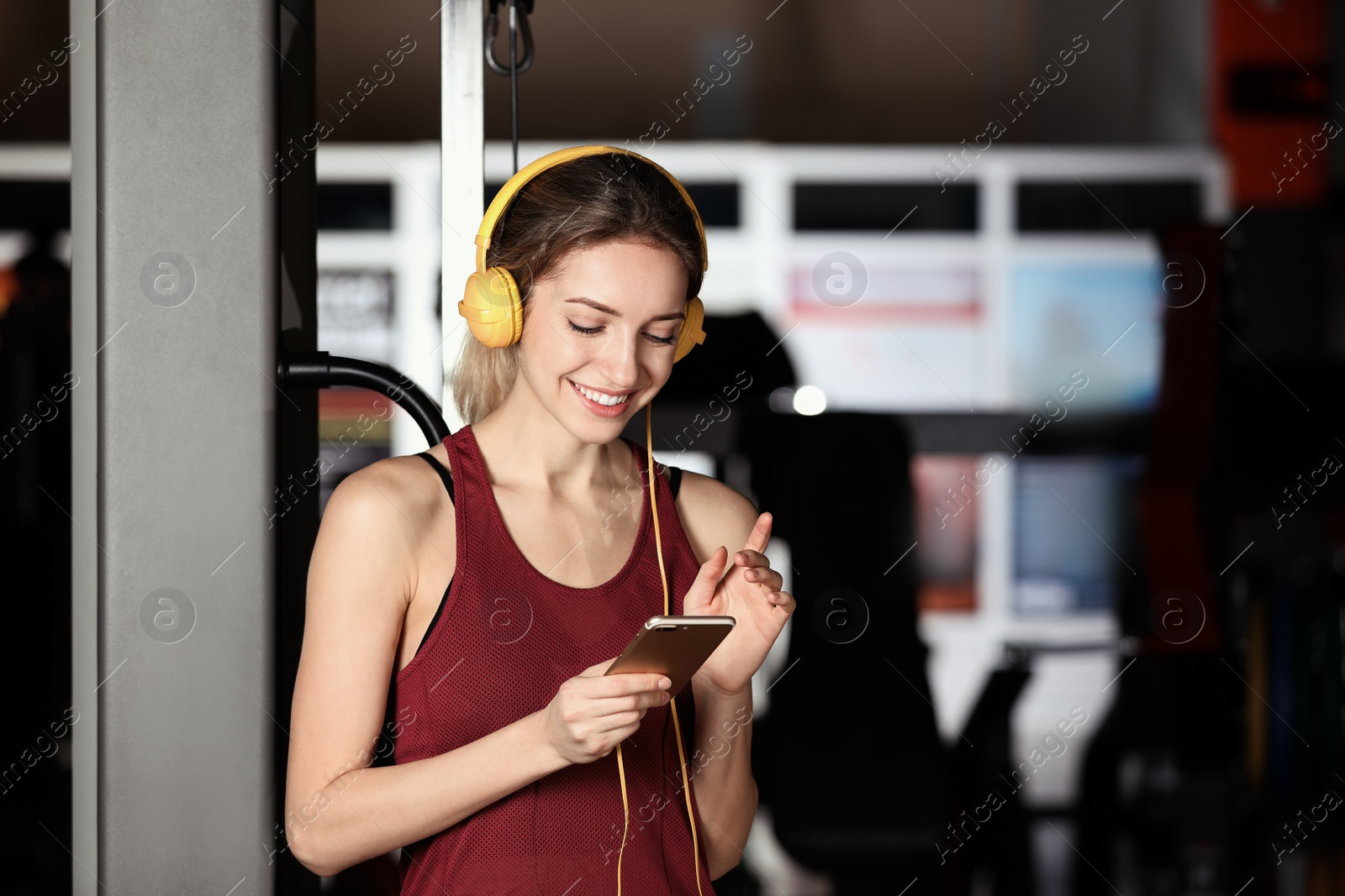 Photo of Young woman with headphones listening to music on mobile device at gym