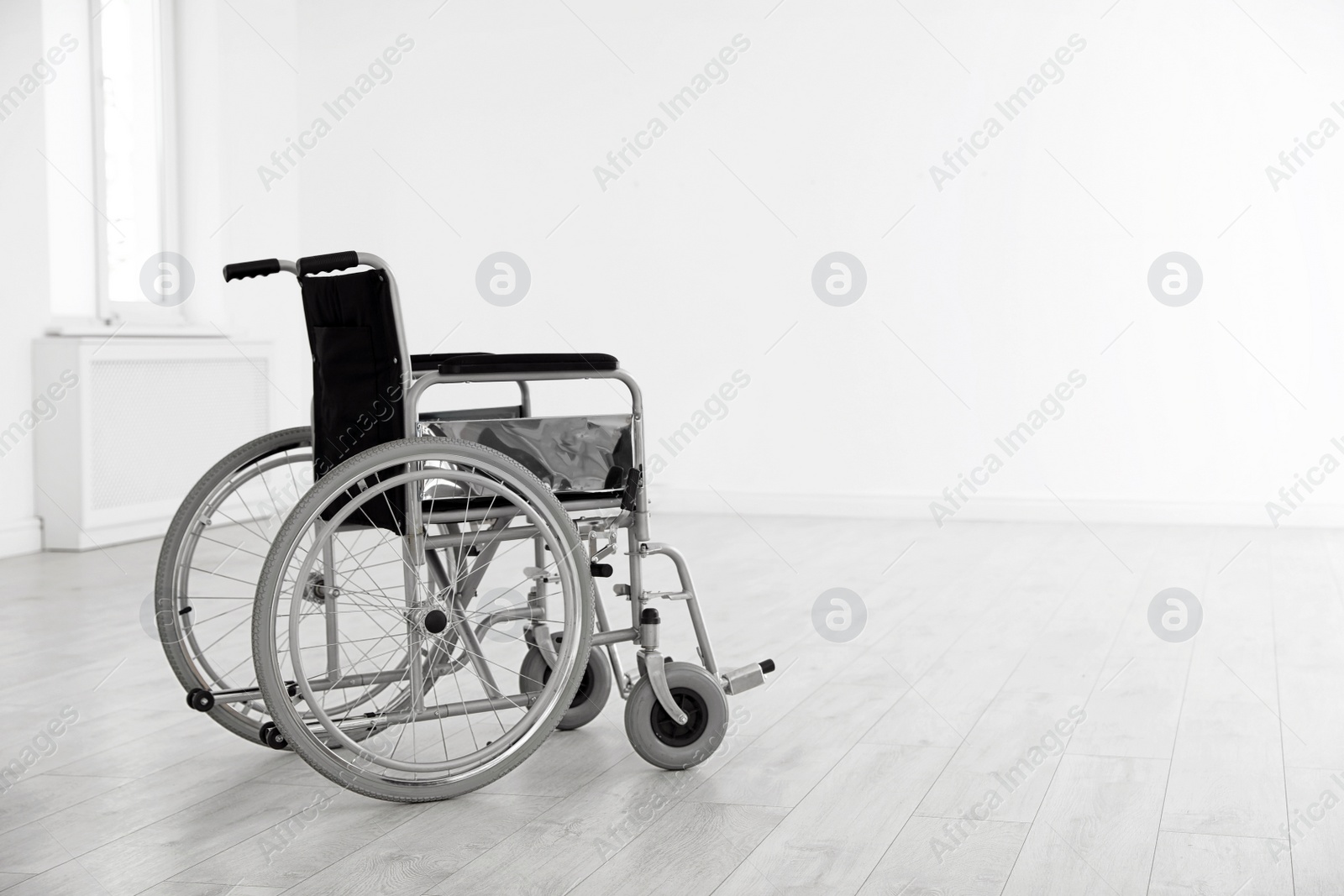 Photo of Modern wheelchair in empty room, space for text. Medical equipment