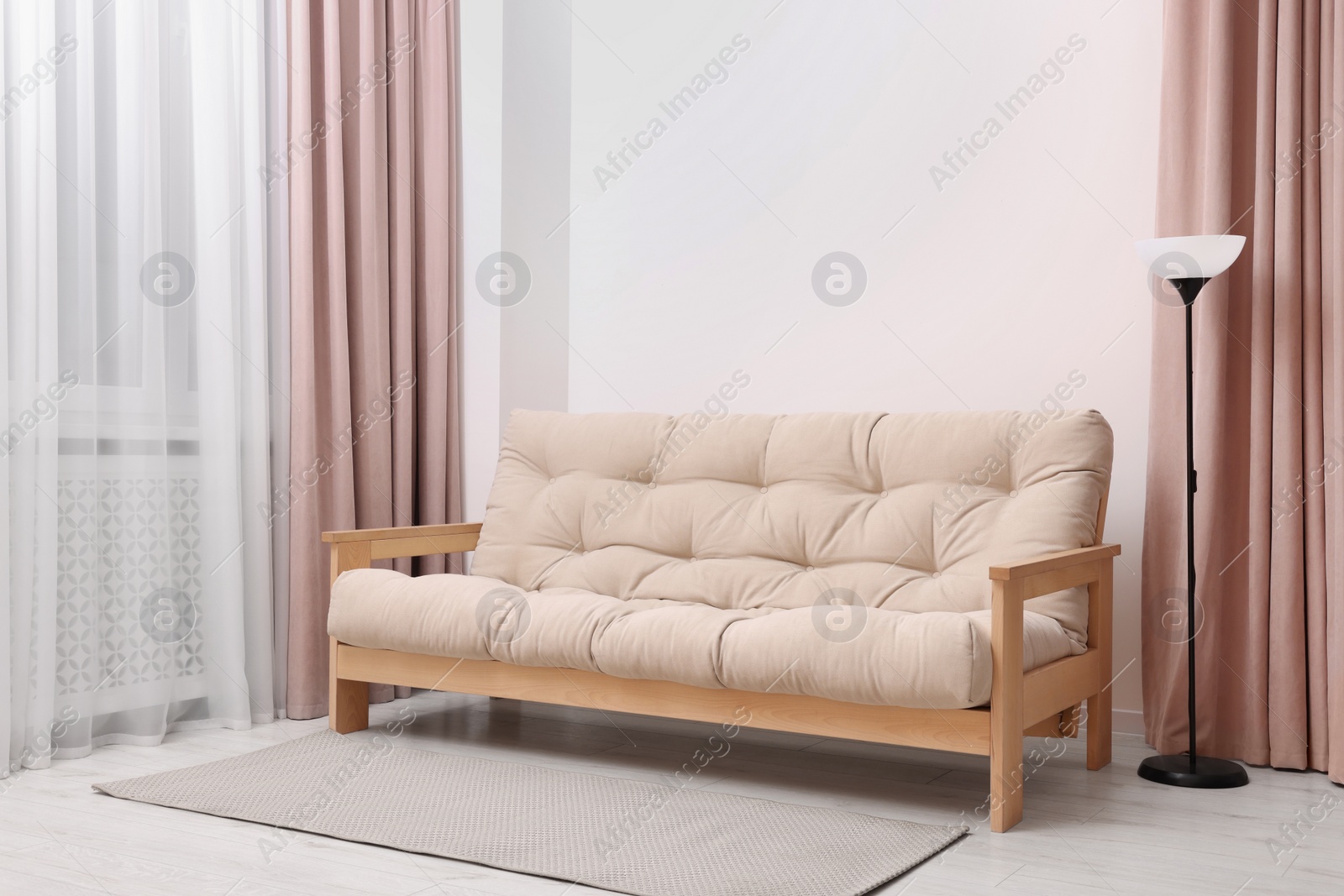 Photo of Comfortable sofa and lamp in cozy light room. Interior design