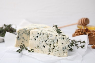 Tasty blue cheese with thyme on white table