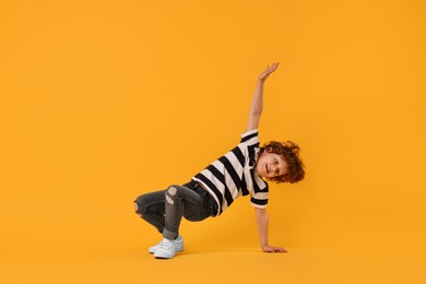 Photo of Happy little boy dancing on yellow background. Space for text