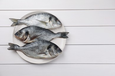 Photo of Fresh raw dorado fish on white wooden table, top view. Space for text