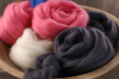 Photo of Colorful felting wool in bowl on table, closeup