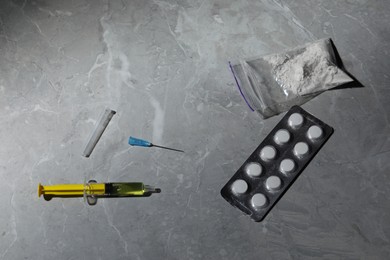 Photo of Pills, syringe and powder on grey marble table, above view. Hard drugs
