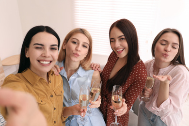 Photo of Beautiful young ladies with champagne taking selfie at home. Women's Day