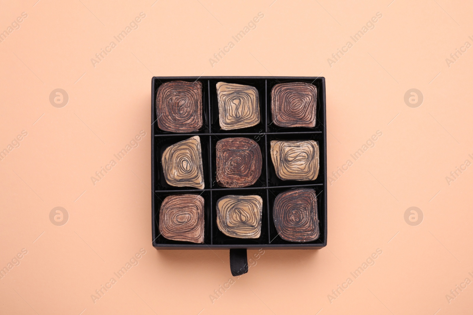 Photo of Box of tasty chocolate candies on beige background, top view