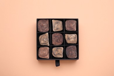 Box of tasty chocolate candies on beige background, top view