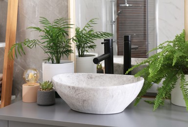 Photo of Stylish vessel sink and beautiful green houseplants in bathroom