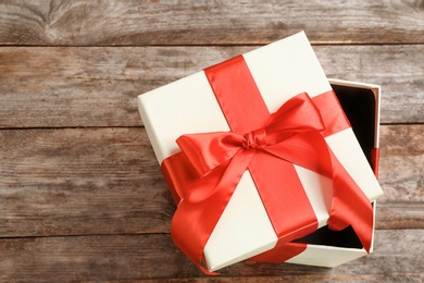 Photo of Elegant gift box with bow on wooden background, top view