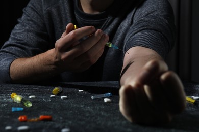 Addicted man taking drugs at black textured table, closeup