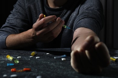 Photo of Addicted man taking drugs at black textured table, closeup