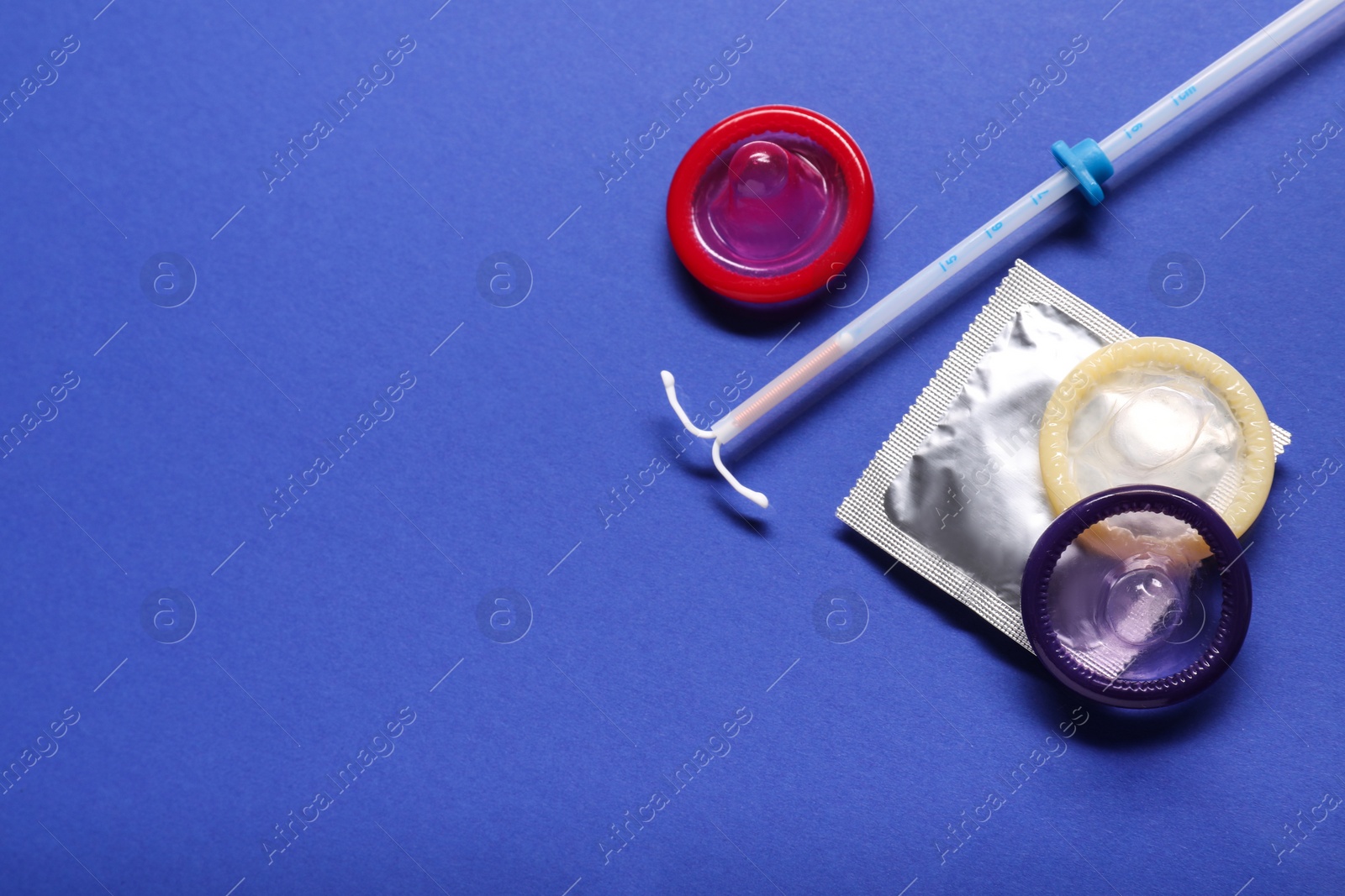 Photo of Condoms and intrauterine device on blue background, flat lay and space for text. Choosing birth control method