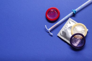 Condoms and intrauterine device on blue background, flat lay and space for text. Choosing birth control method