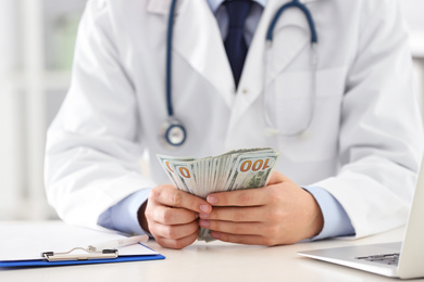 Photo of Doctor with bribe at desk in clinic, closeup. Corrupted medicine