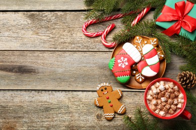 Photo of Different tasty Christmas cookies, decor and cocoa with marshmallows on wooden table, flat lay. Space for text