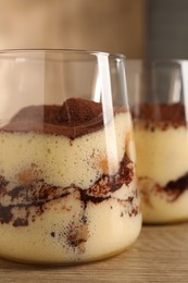 Delicious tiramisu in glasses on wooden table, closeup