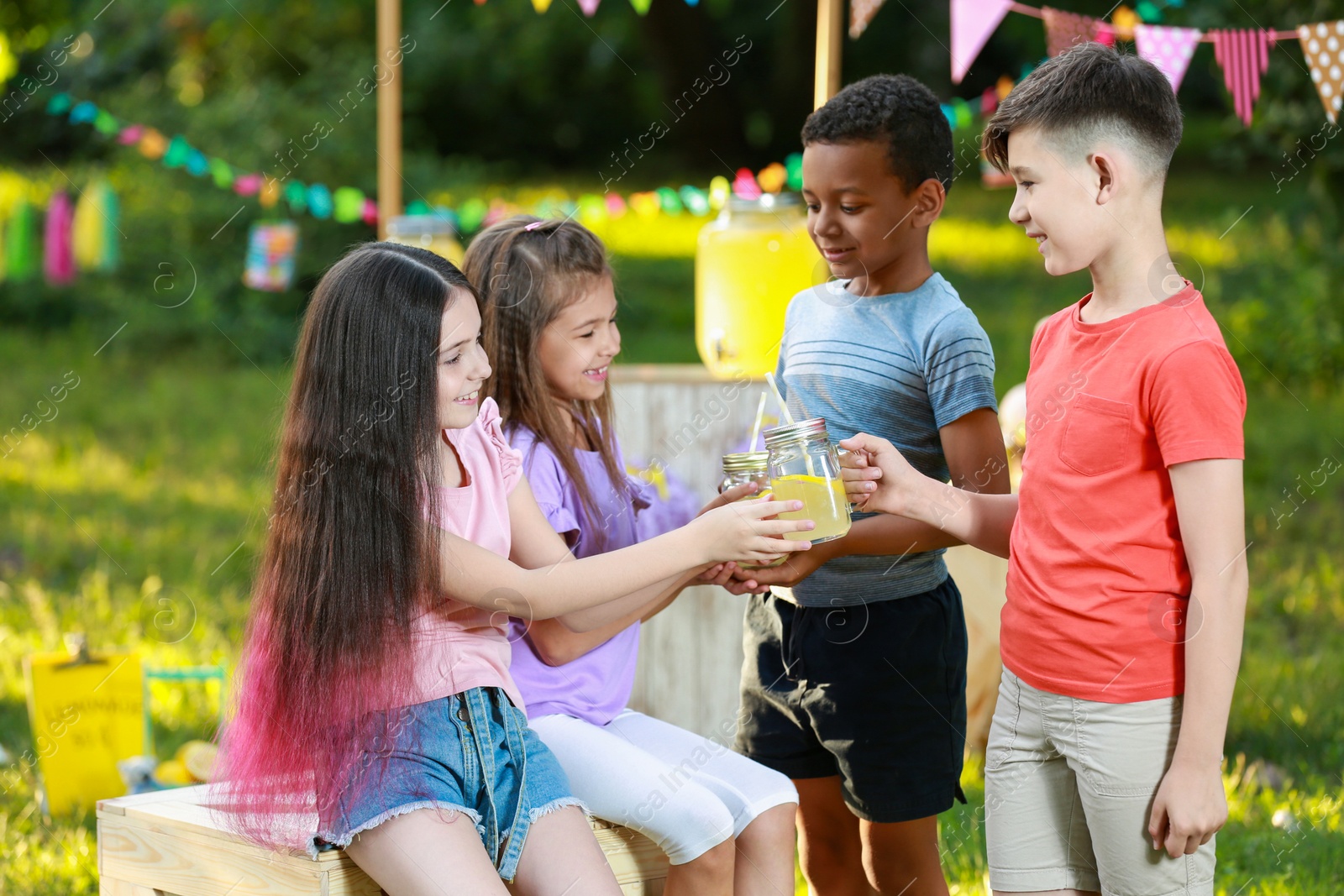 Photo of Cute little children with natural lemonade in park. Summer refreshing drink