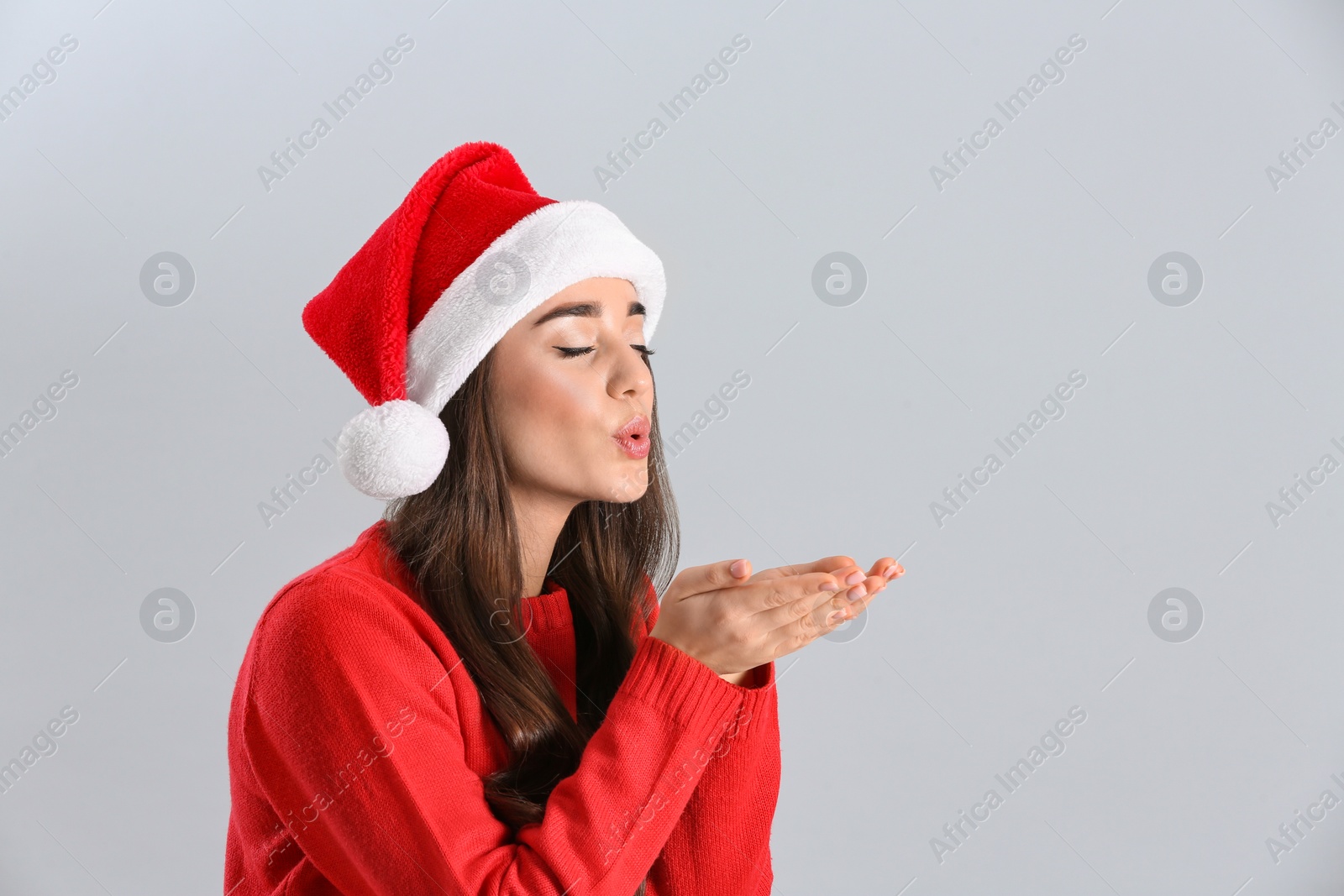 Photo of Beautiful woman wearing Santa Claus hat on light grey background