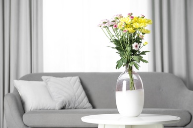 Photo of Vase with beautiful flowers on table in living room, space for text. Stylish element of interior design
