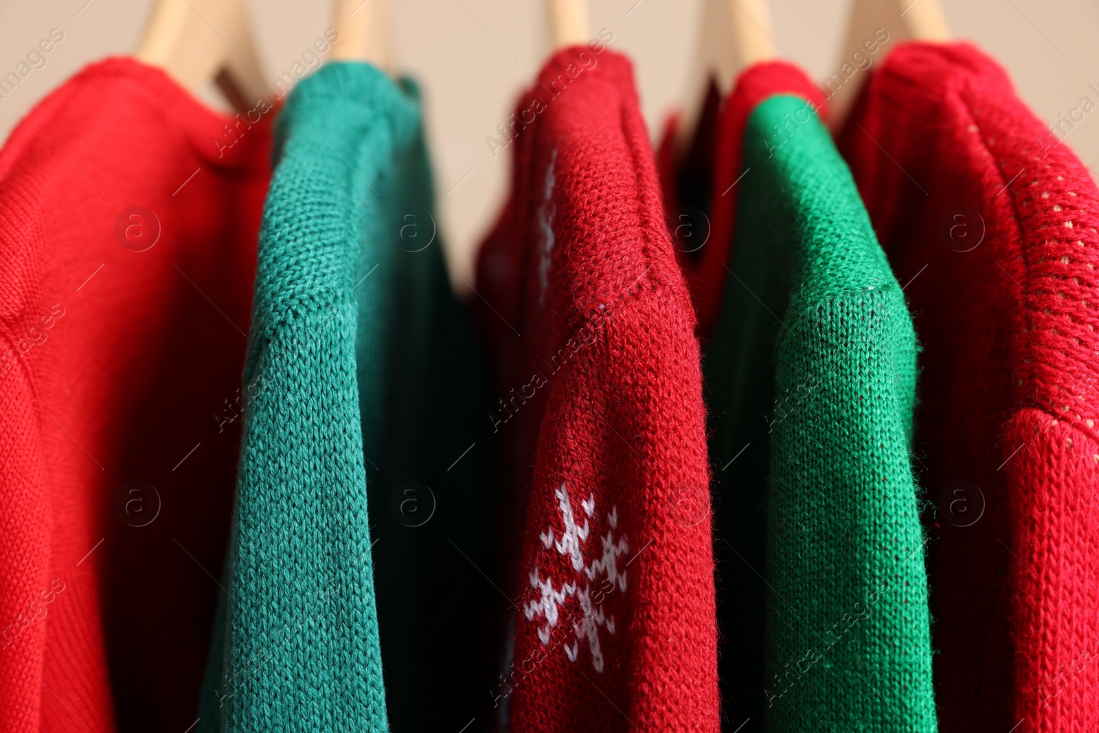 Photo of Different Christmas sweaters hanging on rack, closeup