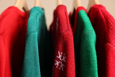 Different Christmas sweaters hanging on rack, closeup