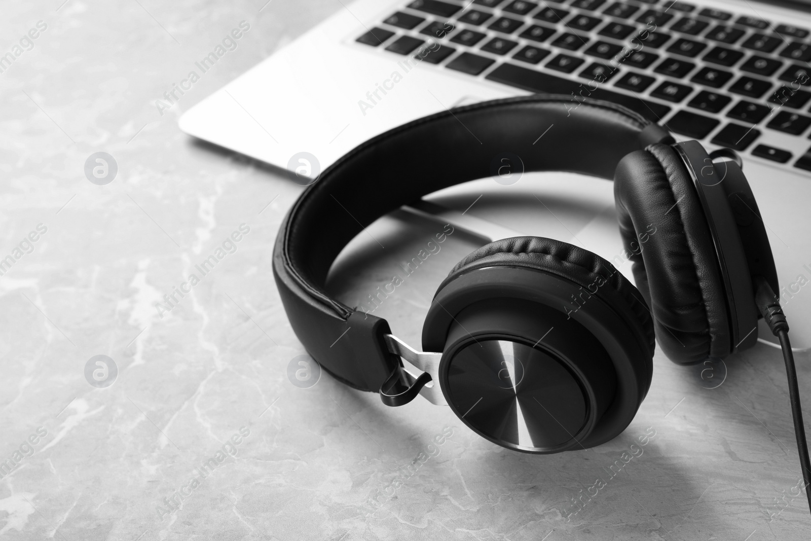 Photo of Modern headphones and laptop on table. Space for text