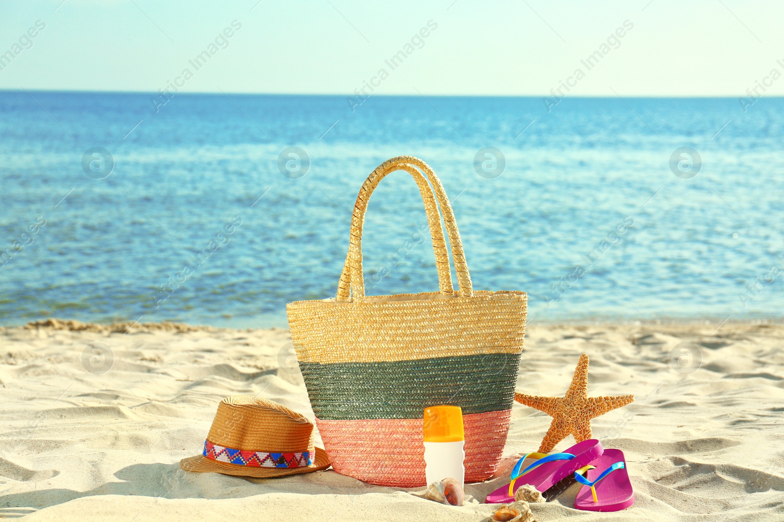 Photo of Composition with stylish beach accessories on sand near sea