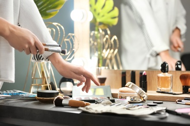 Photo of Professional makeup artist near dressing table with decorative cosmetics in beauty salon