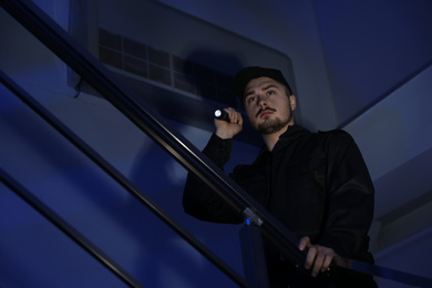 Male security guard with flashlight on stairs in darkness