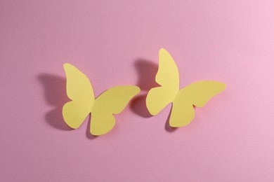 Photo of Yellow paper butterflies on pink background, top view