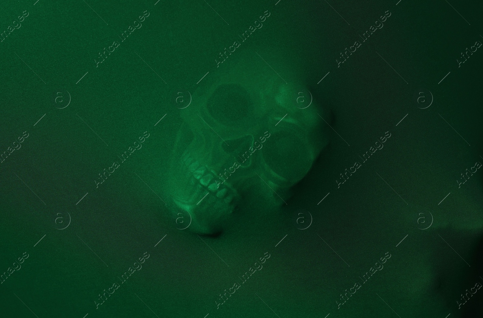 Photo of Silhouette of creepy ghost with skull behind green cloth