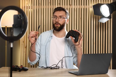 Technology blogger with game controller recording video review at home